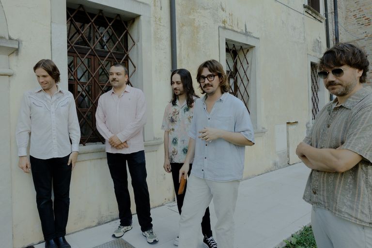 Psych-rock band Altın Gün posing outdoors against a light building wall.